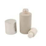 A 1.69 oz (50 ml) clear glass Boston Round bottle with big overcap featuring a sleek black treatment pump. The classic curved-shoulder design highlights a professional and timeless packaging solution for premium skincare brands.