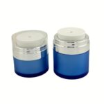 A group of clear and silver refillable airless jars in three sizes, showing the push-down pump actuator and sleek cylindrical design.