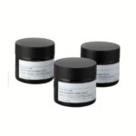 A clear 2 oz straight-sided glass jar with a black smooth screw-top lid.